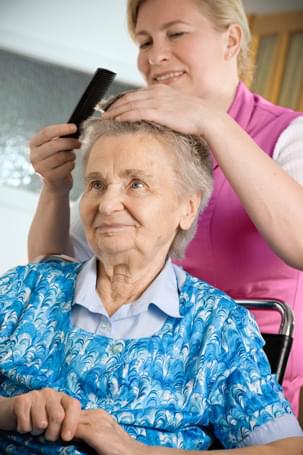 Home carer combing elderly lady's hair